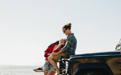 Ein Paar, das mit seinem Auto am Strand steht. Ein glückliches Paar, das während seines Roadtrips am Strand anhält. - JLPSF21160