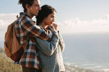 Romantic couple admiring a view from mountain. Loving man and woman in vacation standing on the cliff together and looking at the view. - JLPSF21211