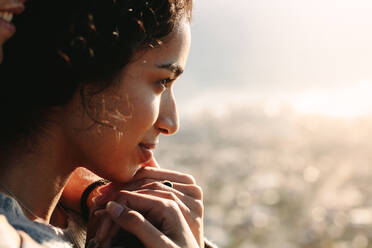 Close up of young woman face looking at a view outdoors. Female being embraced by her man from behind. - JLPSF21213