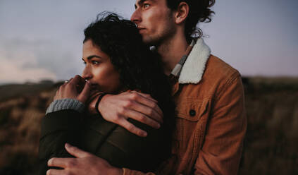 Portrait of couple in love standing together on mountain peak and looking at view. Loving man and woman in warm wear looking at landscape view from mountain. - JLPSF21273