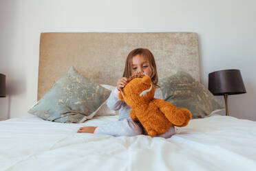 Cute little baby girl putting a crown on her teddy bear. Innocent girl child playing with her soft toy. - JLPSF21420