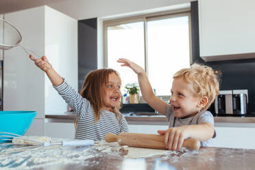 Lustige kleine Kinder bereiten den Teig für Kekse in der Küche vor. Geschwister backen Kekse und haben Spaß in der Küche. - JLPSF21458