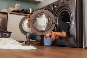 Kleine Kinder spielen zu Hause mit der Waschmaschine. Kinder haben Spaß mit Waschmaschinen. - JLPSF21485