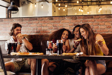 Eine Gruppe von Freunden isst Pizza in einem Café. Fröhliche junge Leute essen Pizza und genießen es in einem Fast-Food-Restaurant. - JLPSF21497