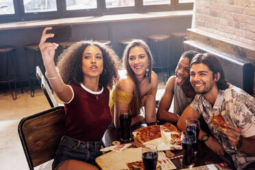 Gruppe von Freunden, die ein Selfie im Restaurant machen. Multi-ethnischer Mann und Frau im Café, die ein Selfie mit dem Handy machen. - JLPSF21510