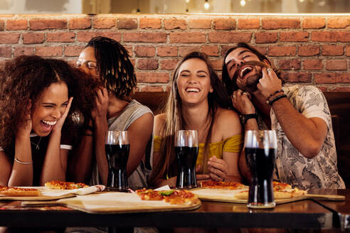 Eine Gruppe glücklicher, multirassischer Freunde feiert eine Party in einem Pizzarestaurant. Fröhliche junge Freunde hängen im Restaurant ab. - JLPSF21513