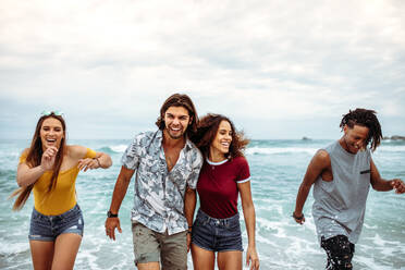 Unbekümmerte Freunde, die sich am Meer vergnügen. Junge Leute, die spazieren gehen und einen Tag am Strandurlaub genießen. - JLPSF21541