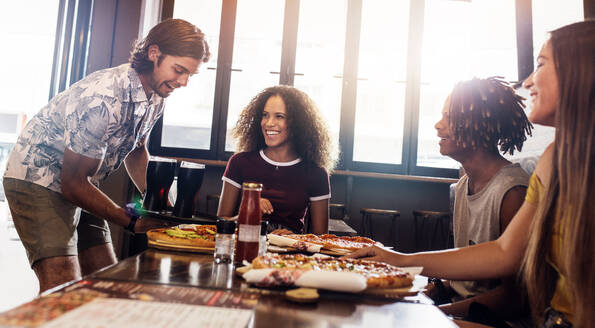 Gruppe von Männern und Frauen in einem Pizzarestaurant. Multiethnische Freunde beim gemeinsamen Mittagessen in einem Schnellrestaurant. - JLPSF21593