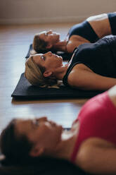 Frauen beim Pilates-Workout im Fitnessstudio. Frauen auf dem Boden liegend mit erhobenem Rücken beim Pilates-Workout. - JLPSF21613