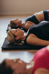 Frauen auf dem Boden liegend mit erhöhtem Rücken tun Pilates-Training. Fitness-Frauen im Fitnessstudio auf dem Boden liegend tun Pilates-Training. - JLPSF21614