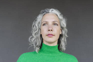 Thoughtful woman with curly hair in front of wall - SEAF01458