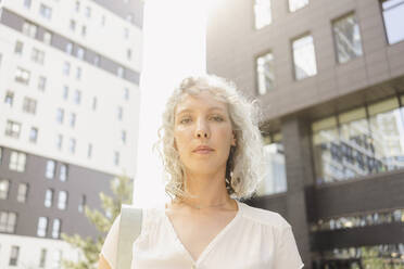 Geschäftsfrau mit grauem lockigem Haar vor einem Gebäude - SEAF01497