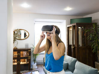 Happy young woman wearing VR goggles - AMRF00116