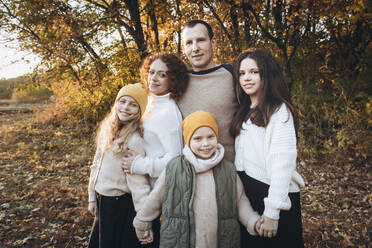 Glücklicher Mann mit Familie im Herbstwald stehend - YLF00022