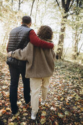 Paar, das sich umarmt und im Wald spazieren geht - YLF00025