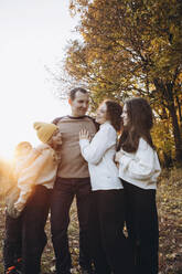 Glücklicher Mann mit Familie im Wald an einem sonnigen Tag - YLF00034