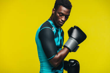 Afrikanischer Mann mit Boxhandschuhen vor gelbem Hintergrund. Fitter junger männlicher Boxer beim Training. - JLPSF21748