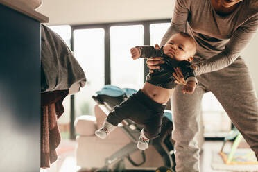 Ausschnitt einer Frau, die sich nach vorne beugt und ihr Baby schaukelt. Eine Mutter verbringt Zeit mit ihrem Baby zu Hause und spielt mit ihm. - JLPSF21800