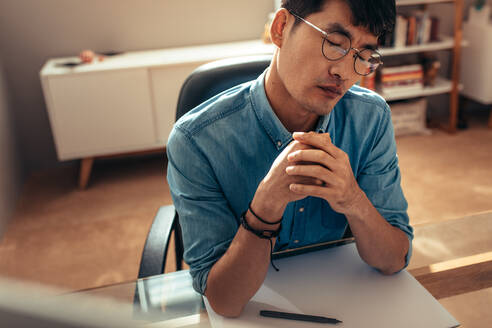 Businessman sitting at his work desk and thinking for new ideas. Designer with dawning book on tablet thinking with his eyes closed. - JLPSF21834