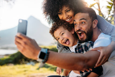 Fröhliche Familie im Urlaub genießen im Freien nehmen selfie. Fröhlich Mann, der ein selfie mit seiner Frau und Kind mit Handy. - JLPSF21901