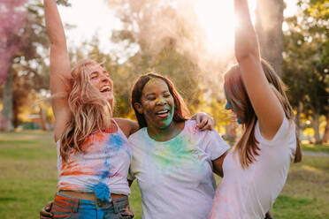 Frauen Freunde genießen Holi mit Pulver Farben und tanzen in Freude. Gruppe von drei Frauen Freunde spielen Holi in einem Park. - JLPSF22000