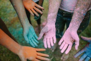 Freunde zeigen ihre bunten Hände beim Holi-Spielen in einem Park. Nahaufnahme von Händen in verschiedenen Farben beim Holi-Spielen mit Pulverfarben. - JLPSF22005