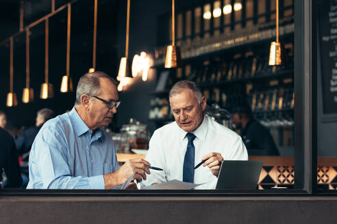Zwei Menschen im Restaurant sitzen am Fenster und beraten sich über ein Projekt. Ältere Männer besprechen ein Geschäftsdokument in einem Café. - JLPSF22013