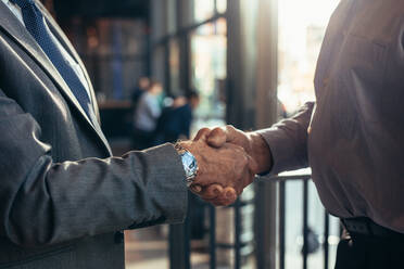 Close up of businessmen handshake at cafe. Cropped shot of two senior business men shaking hands after a deal. - JLPSF22032