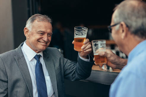 Ältere Geschäftsleute, die nach der Arbeit ein Glas Bier an der Bar trinken. Geschäftsleute, die nach der Arbeit an der Bar etwas trinken. - JLPSF22057