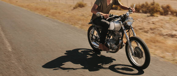 Mann fährt Motorrad auf Landstraße. Ausschnitt eines Mannes auf einem schnell fahrenden Motorrad. - JLPSF22129