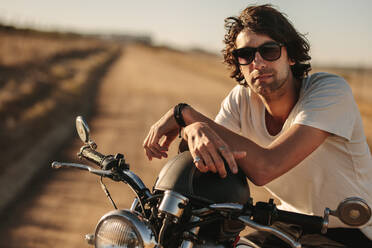 Portrait of handsome young man sitting on his bike on empty country highway. - JLPSF22136