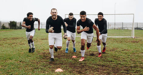 Soccer players running on field shouting in joy after winning the match. Players celebrating success screaming in joy and running on field. - JLPSF22186