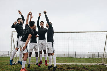 Aufgeregte Fußballspieler, die sich in der Nähe des Torpfostens versammeln und vor dem Spiel jubeln und sich aufmuntern. - JLPSF22196