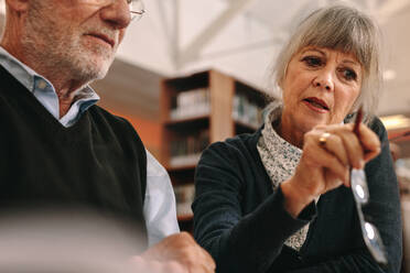 Cropped shot of a senior man and woman learning courses sitting in classroom. Close up of an elderly woman explaining concept to her male colleague. - JLPSF22263