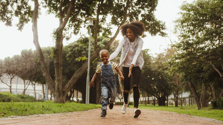 Young mother running with little boy in the park. Happy woman and cute kid having fun outdoors. - JLPSF22296