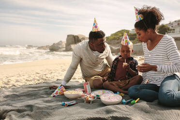 Junge feiert seinen Geburtstag mit Eltern am Strand. Mann und Frau feiern den Geburtstag ihres Sohnes am Strand. - JLPSF22324