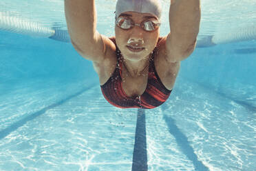 Unterwasseraufnahme einer Schwimmerin, die im Schwimmbad schwimmt. Eine fitte junge Schwimmerin trainiert im Schwimmbad. - JLPSF22391