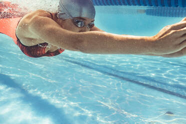 Unterwasseraufnahme einer Schwimmerin im Schwimmbad. Junge Frau schwimmt in einem Sportbecken. - JLPSF22392