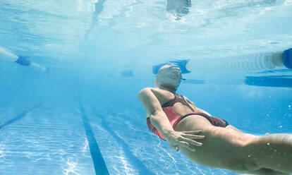 Unterwasseraufnahme einer jungen Schwimmerin, die im Schwimmbecken trainiert. - JLPSF22393