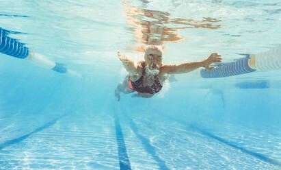 Unterwasseraufnahme einer Schwimmerin beim Schmetterlingsschwimmen im Freibad. Junge Frau schwimmt im Schwimmbad. - JLPSF22394