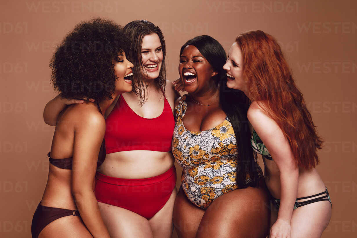 Group of different size females in bikinis laughing together. Multi-ethnic  women in swimwear having fun