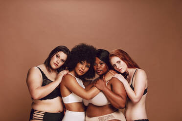 Gruppe von Frauen unterschiedlicher Größe in Dessous, die stolz in die Kamera blicken. Multirassische Frauen in unterschiedlicher Unterwäsche posieren zusammen. - JLPSF22466