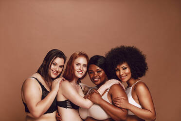 Gruppe verschiedener Frauen mit natürlichen Körpern in Dessous, die lächelnd in die Kamera schauen. Multirassische Frauen, die stolz auf ihre Körper sind. - JLPSF22467