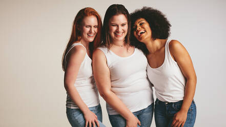 Unterschiedliche Gruppe von Frauen lachen zusammen auf weißem Hintergrund. Frauen in Freizeitkleidung schauen glücklich zusammen. - JLPSF22486