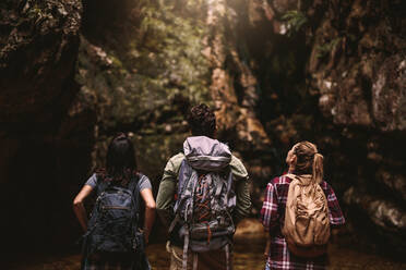 Rear view of three young friends with backpack looking away at mountain view. Group of young people hiking in nature looking at a view. - JLPSF22661