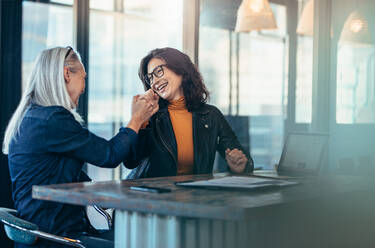 Two business woman giving each other a high five and smiling. Office coworkers rejoicing success. - JLPSF22711