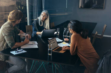 Drei Fachleute, die an einem Tisch sitzen und ihre Arbeit besprechen. Ein Geschäftsteam, das bei einer Besprechung im Büro neue Geschäftsideen entwickelt. - JLPSF22743