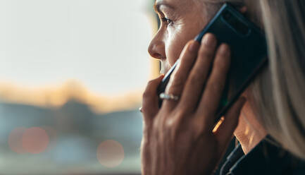 Close up portrait of mature business woman talking over cell phone. Side view of senior business woman making a phone call. - JLPSF22787