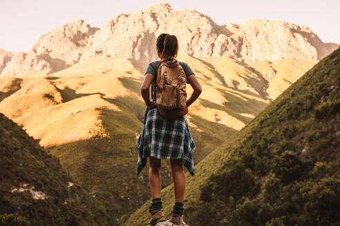 Frau steht auf einem Felsen und blickt auf die Berge. Rückansicht einer Wanderin mit Blick auf die Berglandschaft. - JLPSF22820