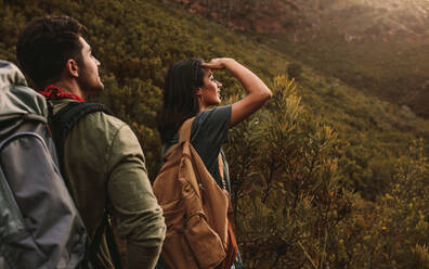 Couple of hiking friends enjoying the view from mountain. Young men and women standing on hilly trail and looking at a view. - JLPSF22826